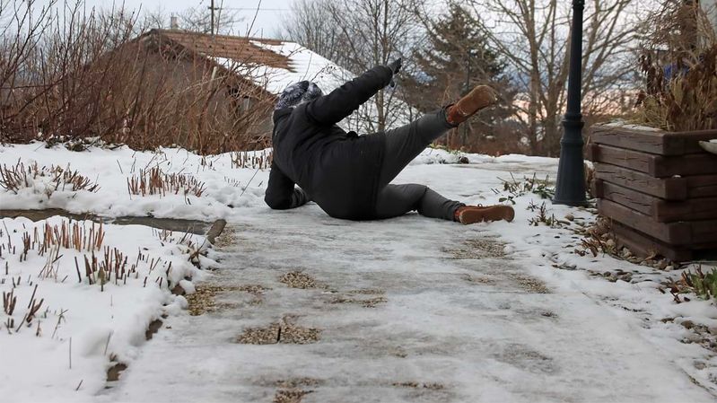 Eine Frau, die auf einem vereisten Weg hinfällt.