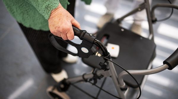 Nahaufnahme eines Rollators, der von einer alten Frau geschoben wird.