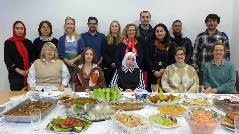 Gruppenbild vor einer reich gedeckten Tafel mit unterschiedlichen Speisen.