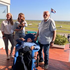 Personen und Hund vor einem Flugplatz
