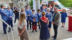 Frauen und Männer stehen in einer Gruppe. Sie sprechen miteinander.