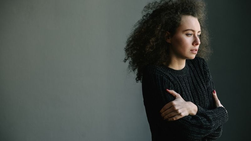 Eine Frau in einem schwarzen Pullover und angelegten Armen 