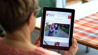 Frau schaut sich das Online-Magazin "dabei" auf einem Tablet an.