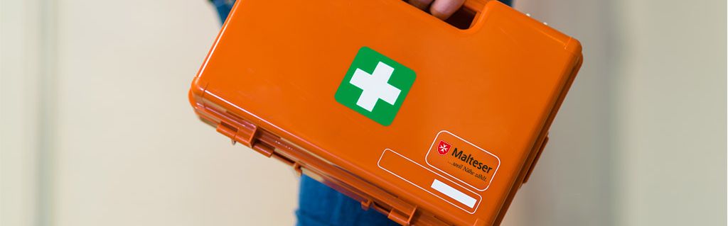 Mann trägt Erste-Hilfe-Kasten