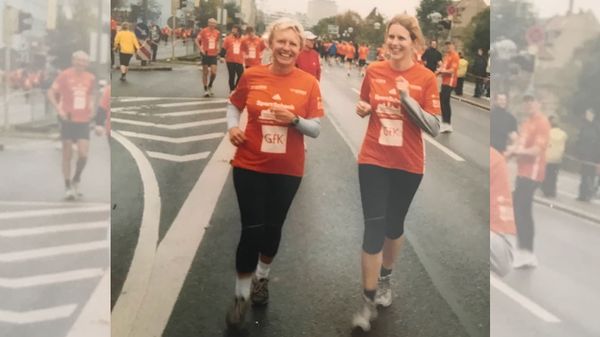 Zwei Frauen in orangefarbenen Trikots bei einer Laufveranstaltung.