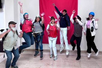 Gruppe von Mitarbeitern in Sportkleidung springt in die Luft.
