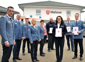 Personengruppe vor Fahrzeug und Gebäude