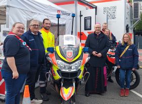 Gruppenbild mit verschiedenen Maltesern, Bischof und Motorrad in der Mitte