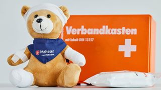 Erste-Hilfe-Verbandskasten mit Teddy, der verbunden und gepflastert ist