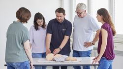 An einer Kinder Dummy Puppe werden erste Hilfe Maßnahmen gezeigt.