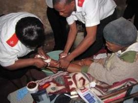 Two care workers tend to an older woman’s arm.