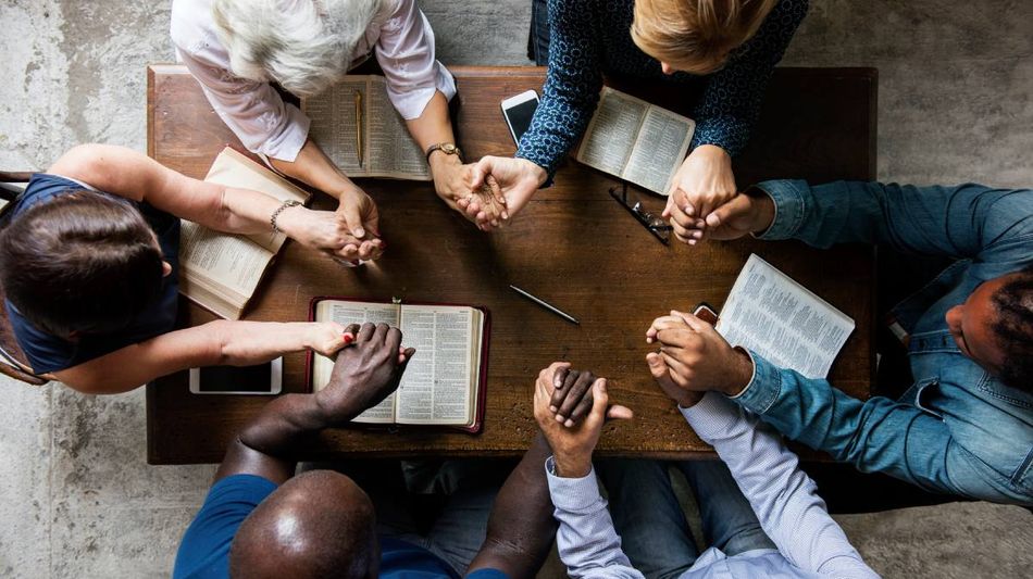  Ein älterer Mann sitzt im Schneidersitz mit geschlossenen Augen und Kopfhörern auf dem Fußboden eines Wohnzimmers.