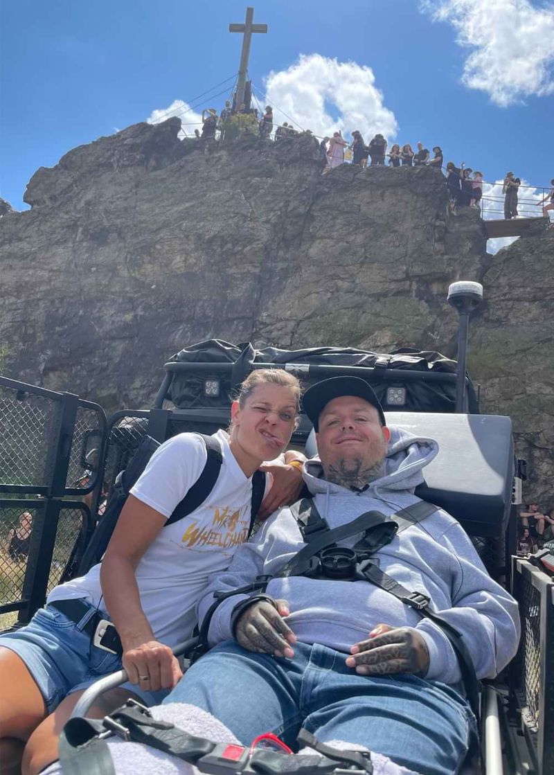 Ein lächelnder Mann und eine Frau, die eine Grimasse schneidet, in einem Spezialfahrzeug vor der Teufelsmauer im Harz.