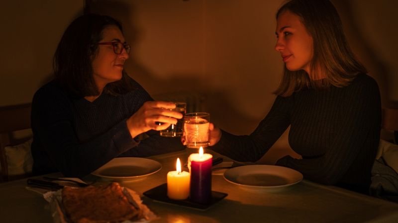 Zwei junge Frauen essen bei Kerzenschein