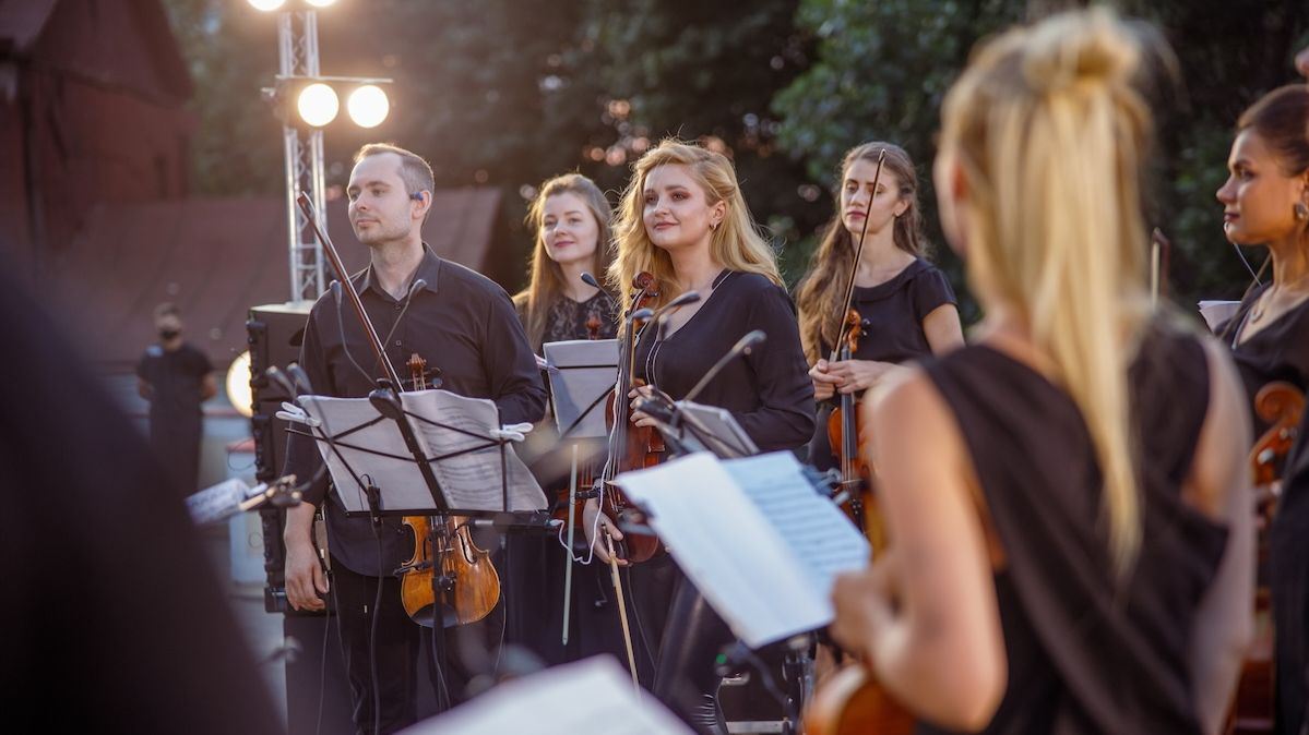 Musikerinnen und Musiker eines Orchesters bei einem abendlichen Auftritt im Freien 