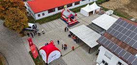 Luftaufnahme eines Hofes mit Solarzellen, Pavillons, einem roten aufblasbaren Zelt und einem roten Einsatzfahrzeug.