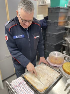 Ortsseelsorger Markus Kemper schneidet den Kuchen an.