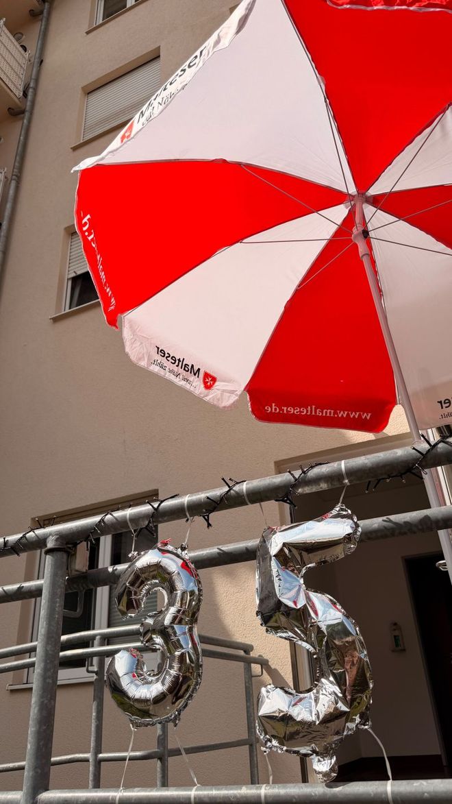 silberfarbene, aufblasbare Zahl 35 hängt am Geländer der Dienststelle Leipzig. Ein Rot-weißer großer Standschirm ist darüber aufgespannt.