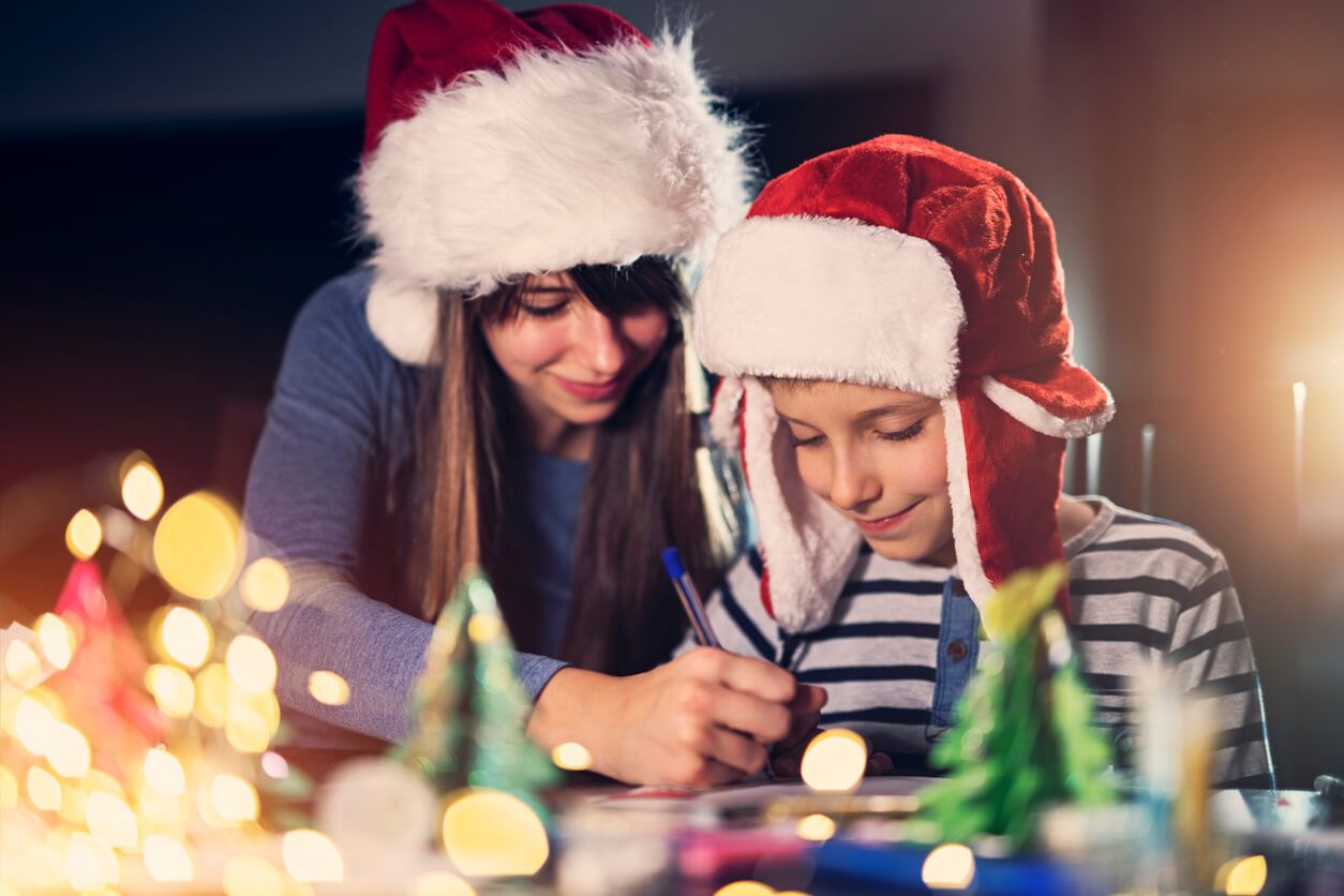 Junge Frau malt mit einem Kind Weihnachtsbilder