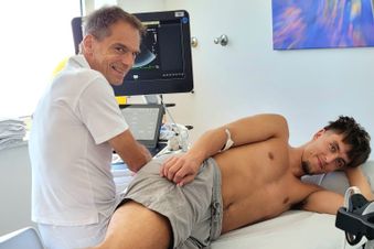 Arzt führt eine Ultraschalluntersuchung bei einem jungen Mann im Behandlungsraum durch.