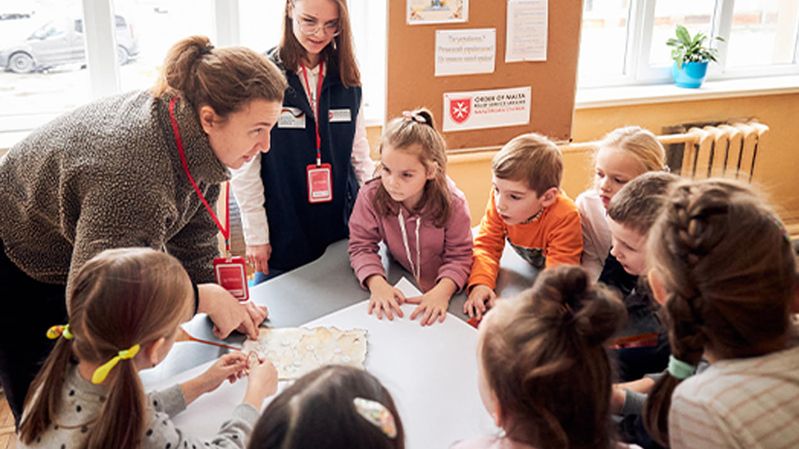 Zwei Frauen und mehrere Kinder an einem Tisch