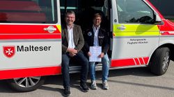 Zwei Männer sitzen bei geöffneter Seitentür in einem Malteser Rettungswagen.