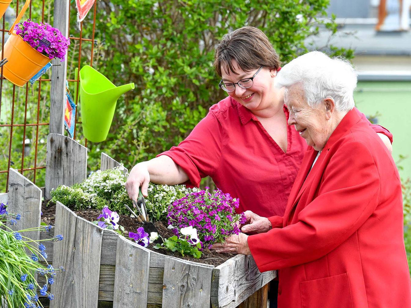 Pflegerin und Bewohnerin legen zusammen ein Blumenbeet an