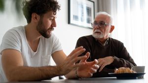 Ein junger Mann mit einem älteren Mann an einem Tisch im Gespräch. 