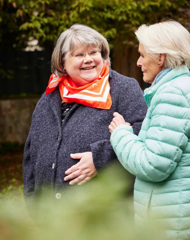 Zwei Frauen stehen im Grünen und unterhalten sich.