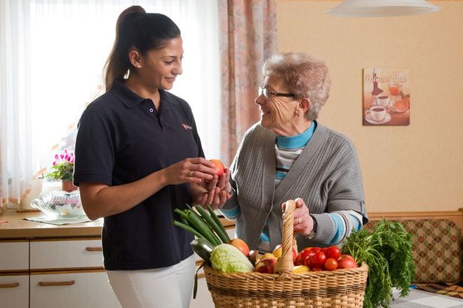 Eine Mitarbeiterin vom ambulanten Pflegedienst der Malteser hilft einer Seniorin bei der Hausarbeit.