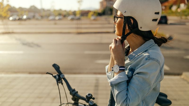 Eine junge Frau legt einen Fahrradhelm an.