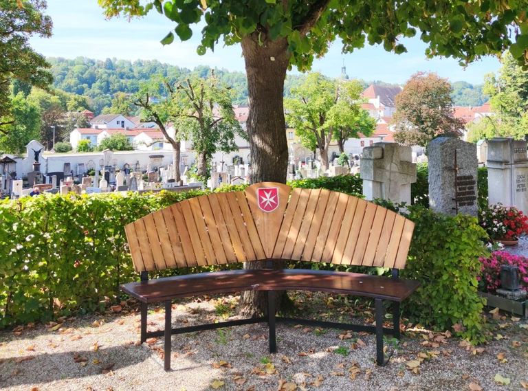 Holzbank mit Malteserlogo auf dem Friedhof