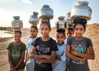 Eine Gruppe von Frauen in Indien, die Blechdosen auf dem Kopf tragen