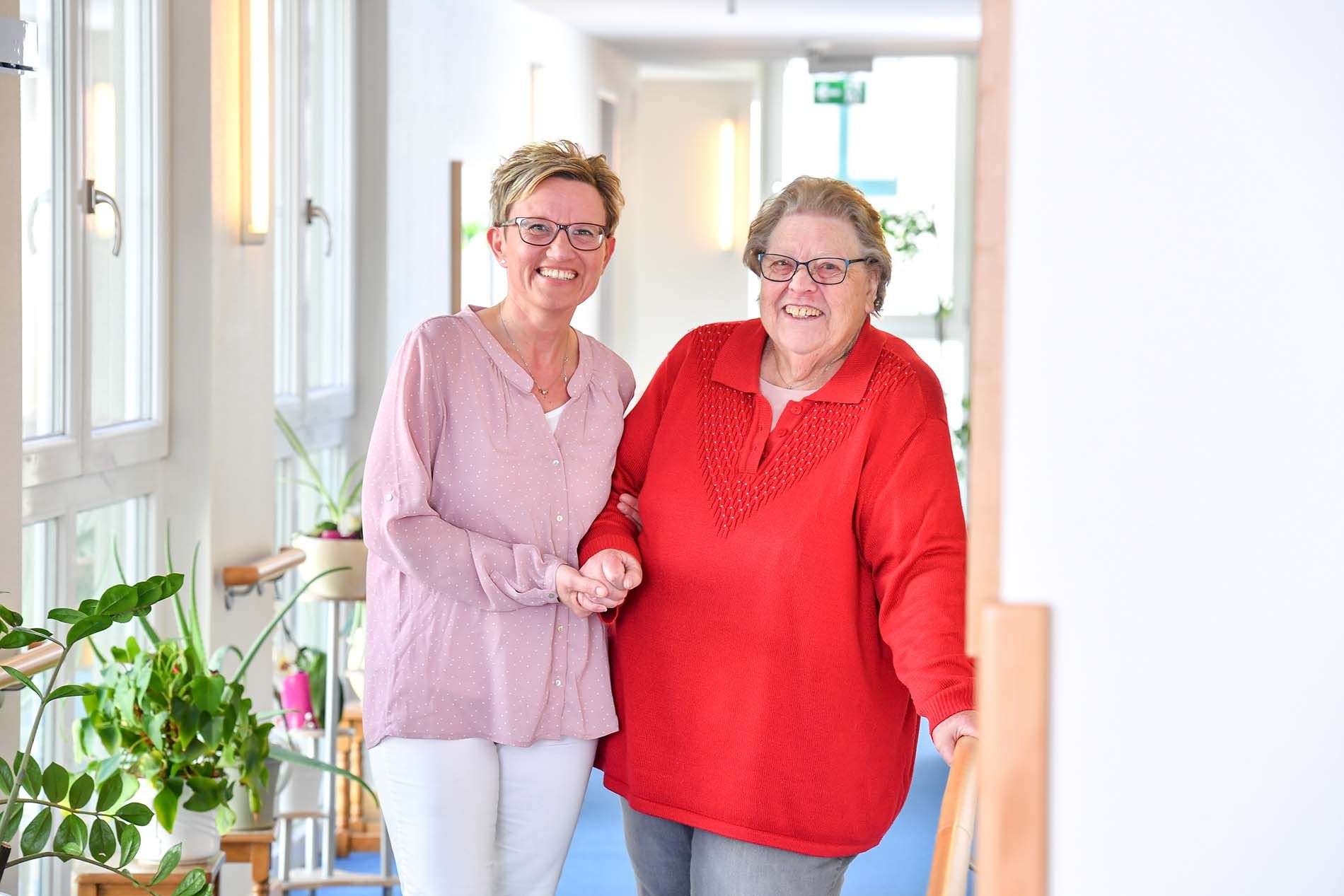Pflegerin begleitet Bewohnerin durch den Flur