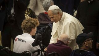 Papst spricht mit einem Malteser im Rollstuhl
