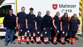 Gruppenbild der neuen Rettungssanitäter mit dem Leiter Einsatzdienste und der Gliederungsärztin vor einem Rettungswagen 