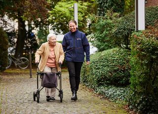 Eine Malteser Mitarbeiterin mit einer Seniorin im Park