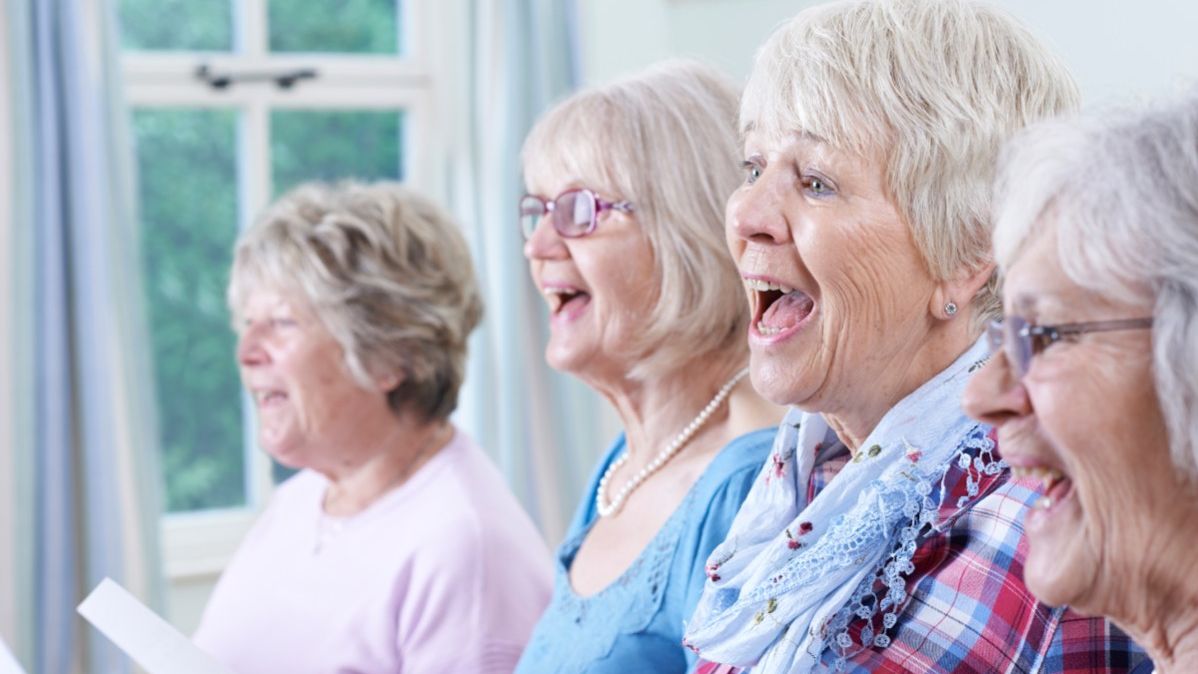 Vier ältere Frauen mit Notenblättern in der Hand singen