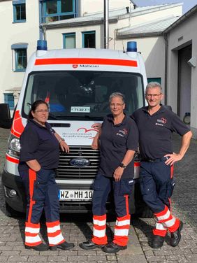 Drei Malteser Helfer stehen vor dem Herzenswunsch-Krankenwagen