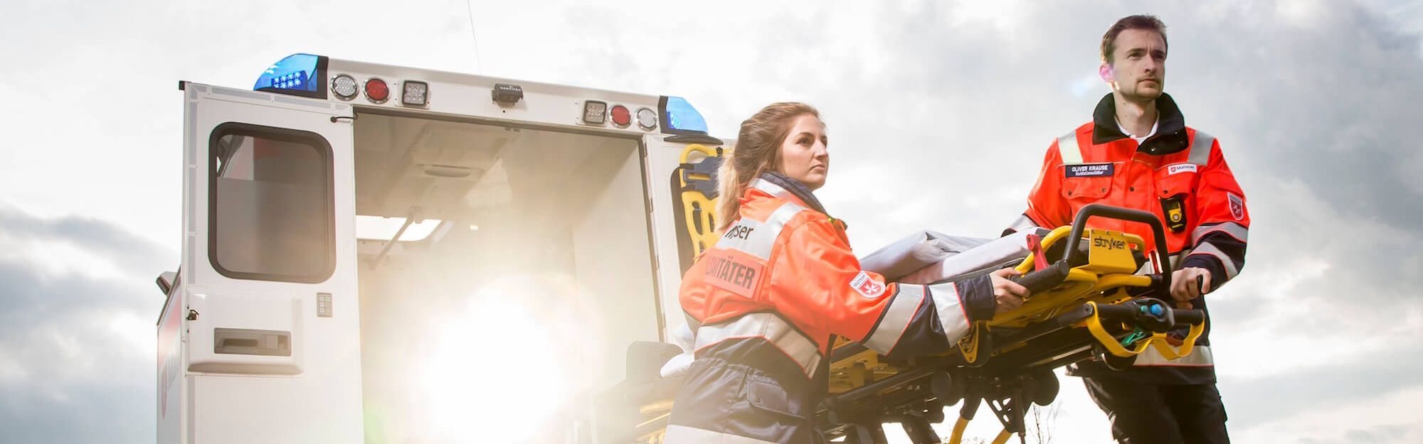 Zwei Rettungssanitäter schieben die Trage aus dem Retungswagen