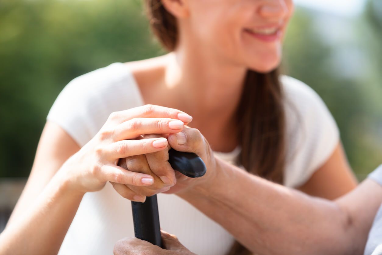 Junge Frau hält die Hände einer älteren Person