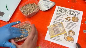 Hände formen aus Haferflocken und Früchten essbare Kugeln