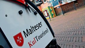 Eine Fahrradrikscha vor einem Hauswandgemälde in Hildesheim