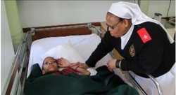 A sister holds Phumulani’s hand beside his bed at the hospice.