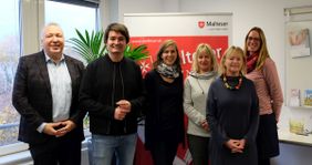 Auf dem Foto sind die Menschen zu sehen, die den NBD zusammen anbieten. Sie stehen als Gruppe zusammen.