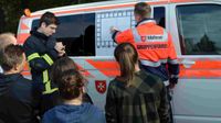 Ein junger Mann in Einsatzkleidung der Malteser mit der Aufschrift „Gruppenführer“ bespricht einen Einsatz vor einer Gruppe junger Menschen.