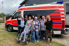 Die Familie steht für ein Gruppenfoto vor dem Herzenswunsch-Krankenwagen.