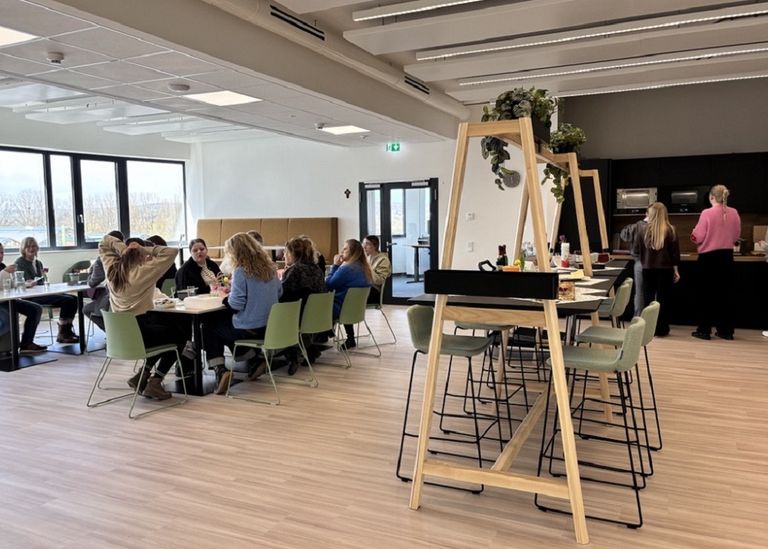 Eine moderne Bürofläche, mit langen Tischen, an denen Menschen sitzen