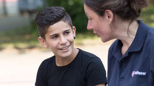 Eine junge Malteser Integrationslotsin unterhält sich mit einem Jungen.