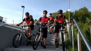 Vier Männer in Signalwesten auf Fahrrädern auf einer Betontreppe.